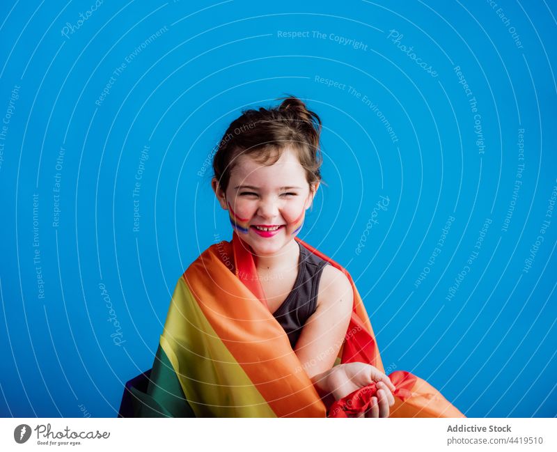 Cheerful girl holding multicolored flag kid child colorful childhood little smile vivid cute toothy smile vibrant stripe innocent adorable delight creative