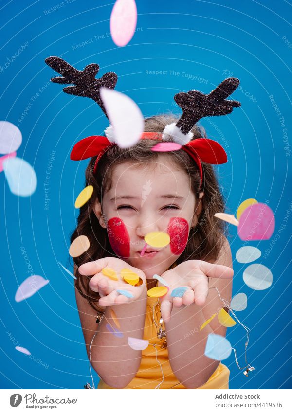 Cute funny girl blowing off multicolored confetti child kid holiday antler deer christmas having fun childhood xmas celebrate headband happy cute colorful joy