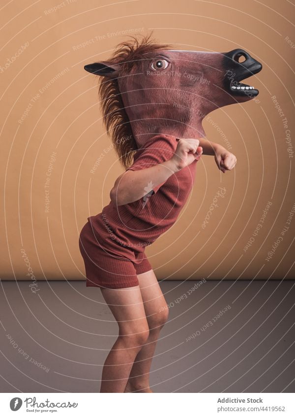 Unrecognizable child in horse mask on floor gallop stallion animal equine motion energy concept dynamic childhood fast lean forward creative design decorative