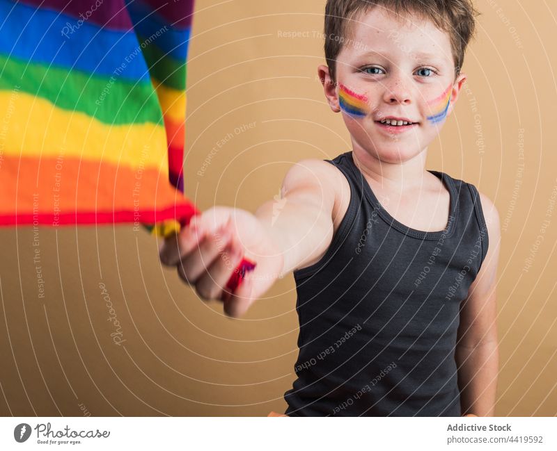 Smiling boy with rainbow flag and striped makeup lgbtq pride equality right freedom smile portrait tolerance solidarity spectrum concept childhood multicolored