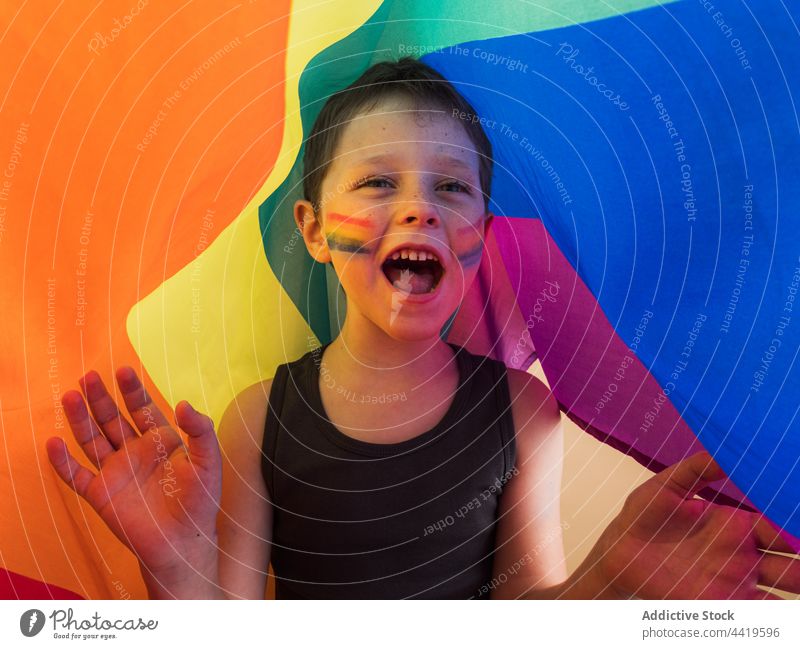 Excited boy with striped makeup screaming under rainbow flag lgbtq excited pride solidarity equality concept mouth opened right freedom smile shout tolerance