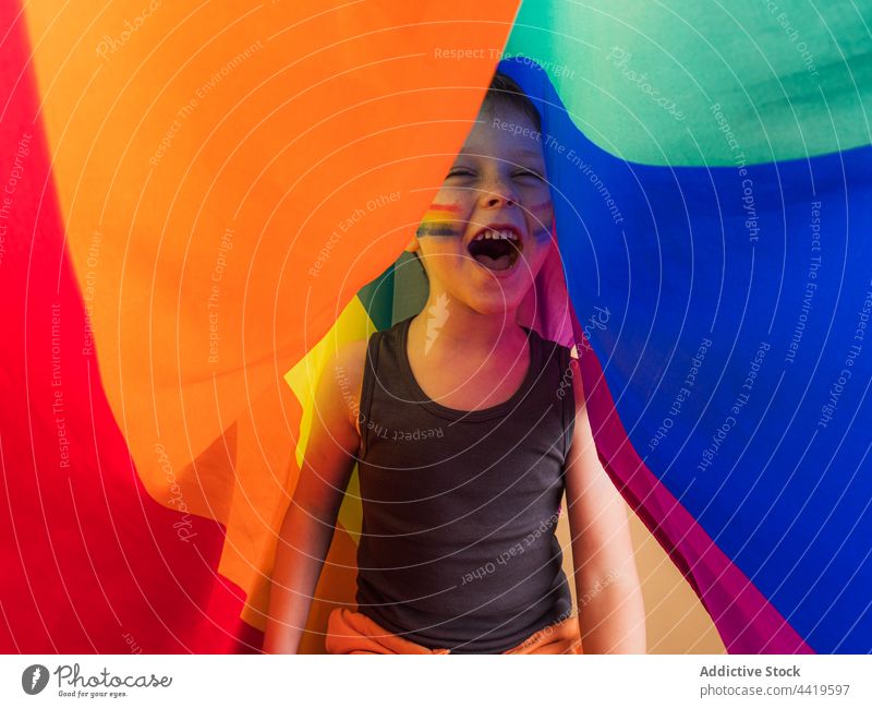 Excited boy with striped makeup screaming under rainbow flag lgbtq excited pride solidarity equality concept mouth opened right freedom smile shout tolerance