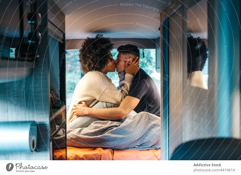 Travelling couple kissing in camper van travel love romantic together relationship tender young boyfriend girlfriend multiracial multiethnic diverse black