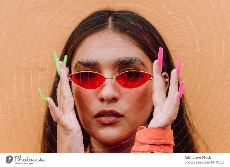 Stylish woman putting on stylish sunglasses portrait confident put on trendy modern style cool long nails looking at camera individuality female long hair