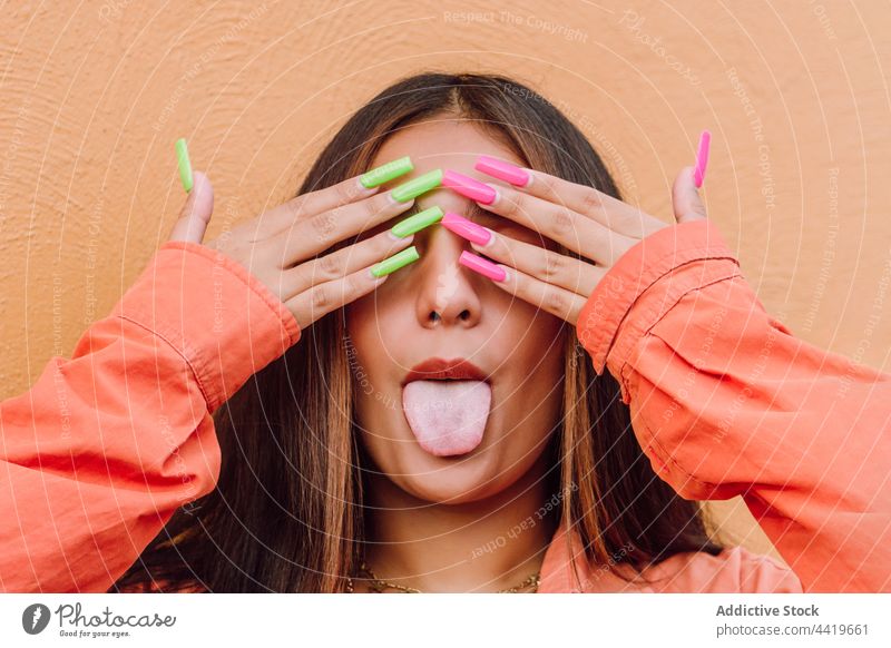 Funny woman with bright long nails showing tongue show tongue portrait naughty grimace tongue out playful childish posture hide female fun make face expressive