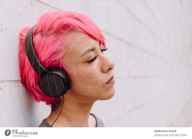 Young woman in headphones with eyes closed music modern dyed hair street bright device urban audio hairstyle female young dreamy appearance individuality listen