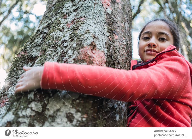 Ethnic girl at old tree trunk in woods bark nature environment ecology preserve forest portrait lichen child conserve protect childhood ethnic rough friendly