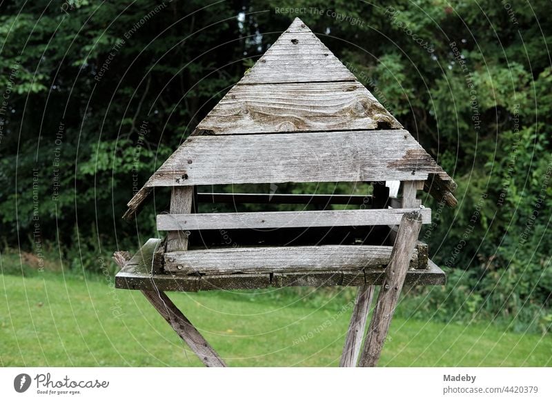 Self-made large wooden bird house with pointed gable in a green garden at the edge of the forest on a farm in Rudersau near Rottenbuch in the district of Weilheim-Schongau in Upper Bavaria
