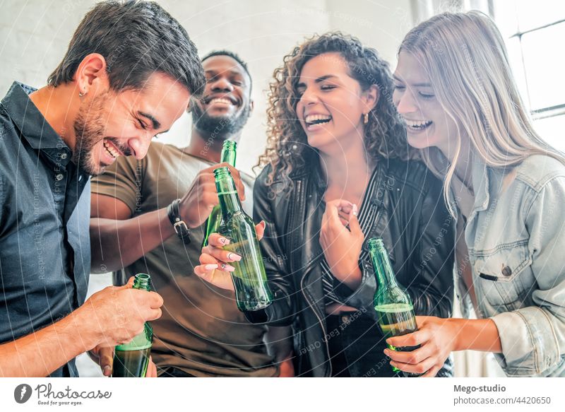 Friends having fun while drinking beer together. home group friends happy friendship party smile cheers female smiling happiness enjoy man woman indoors bottle