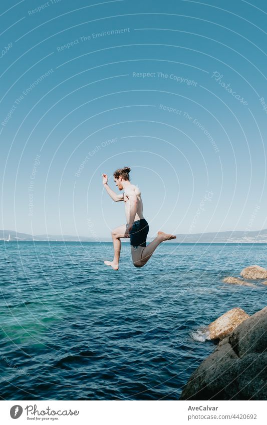 Young man jumping into the sea, in the air, mediterranean holidays, freedom and liberty concepts, modern, pale man horizontal shirtless young adult carefree