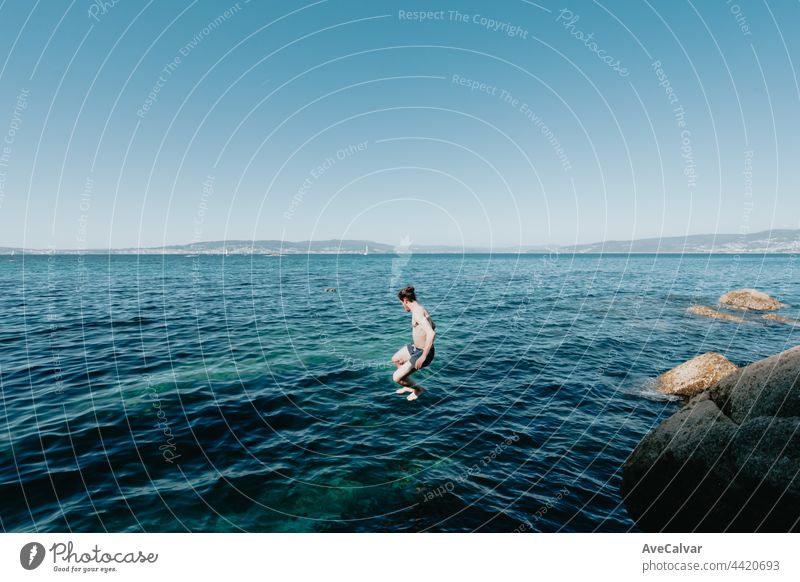 Young man jumping into the sea, in the air, mediterranean holidays, freedom and liberty concepts, modern, pale man horizontal shirtless young adult carefree
