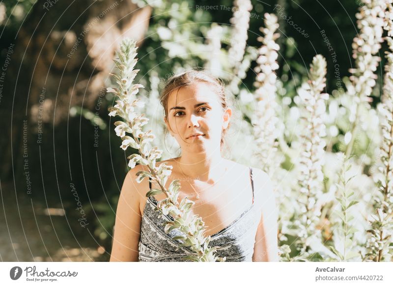 Portrait of a serious young woman near some flowers, mental health and self care concepts, psychology, young loneliness portrait meadow relaxation resting