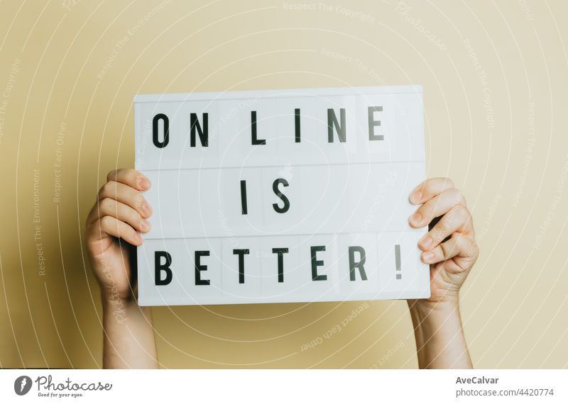 Two hands holding a sign that says online is better over a pastel yellow background, styling and design concept, copy space, buy online and e-commerce shopping