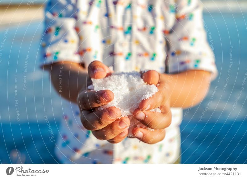 A small boy holding salt crystals in his hands at salines in Faro, Algarve, Portugal industry production child close up people copy space show kid palm human