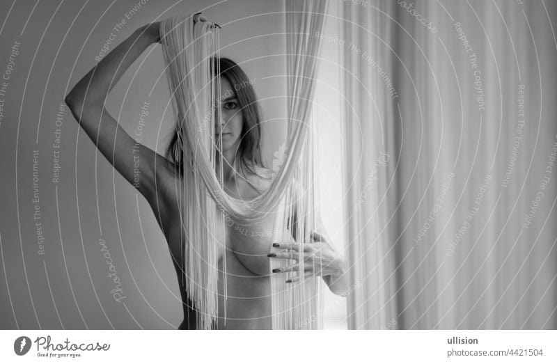 naked body of a young woman, partially obscured by a falling string curtain, with copy space, space for text. black-and-white Black and white image monochrome