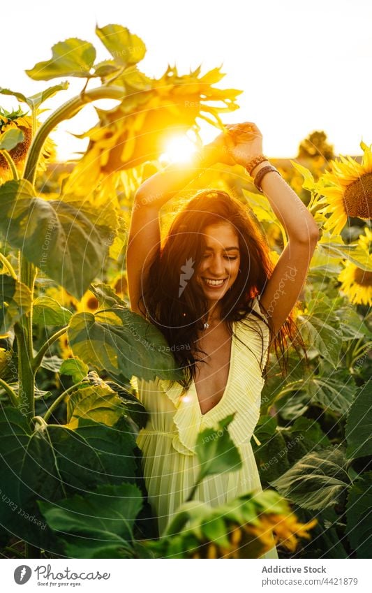Cheerful woman in yellow dress in sunflower field style summer fashion grace female young hispanic boho bohemian nature bloom countryside arms raised romantic