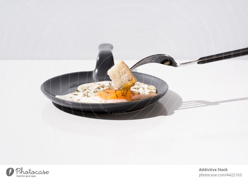 Fork with piece of bread dipped in yolk of fried egg fork skillet food breakfast dish meal delicious portion tasty cuisine fresh minimal simple plain appetizing