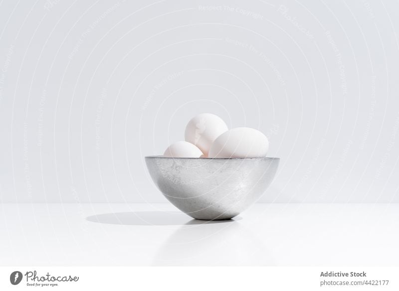 White chicken eggs in bowl on table pile fresh white color studio minimal natural style food healthy nutrition simple plain desk organic raw easter holiday