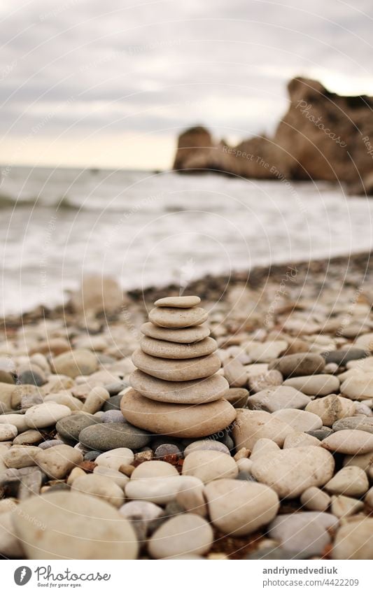 Pyramid stones on the seashore on a sunny day on the blue sea background. Happy holidays. Pebble beach, calm sea, travel destination. Concept of happy vacation on the sea.