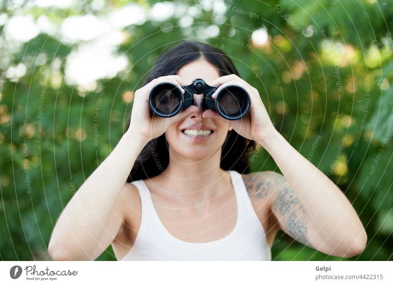 Brunette woman looking through the binoculars while strolling through a forest hiking female travel adventure activity hiker lifestyle nature happy person zoom