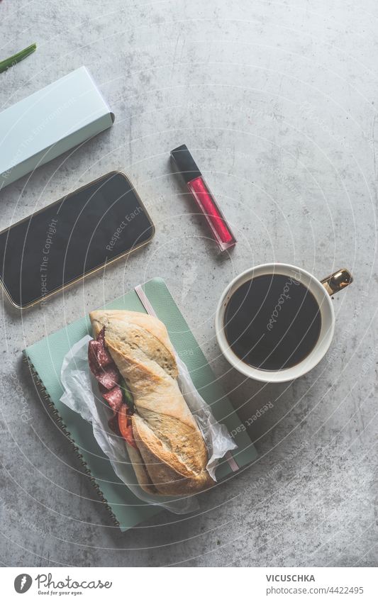 Sandwich lunch or breakfast on gray desk with coffee, smartphone and cosmetic , top view. sandwich tool black mock up snack vegetable bread business lifestyle