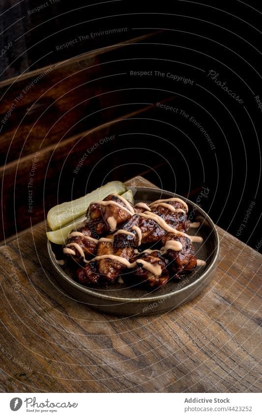 Plate with grilled chicken wings in barbeque sauce food dish restaurant delicious serve roast fast food meal cucumber bbq meat tasty cuisine portion plate fried