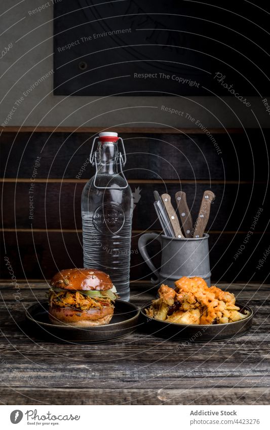 Appetizing burger and crispy chicken placed on table in restaurant fast food tasty yummy dish gourmet delicious meal plate fried portion serve bottle glass