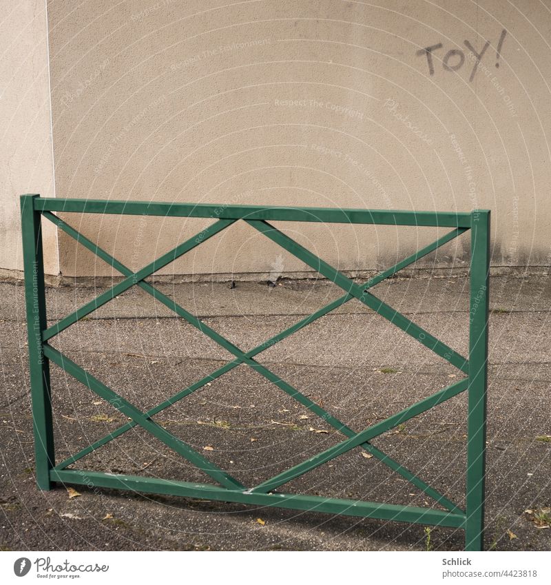 Toy with exclamation mark written on a wall toy Text writing Wall (building) Sidewalk rail Graffiti Asphalt Green Gray Beige Copy Space nobody Deserted
