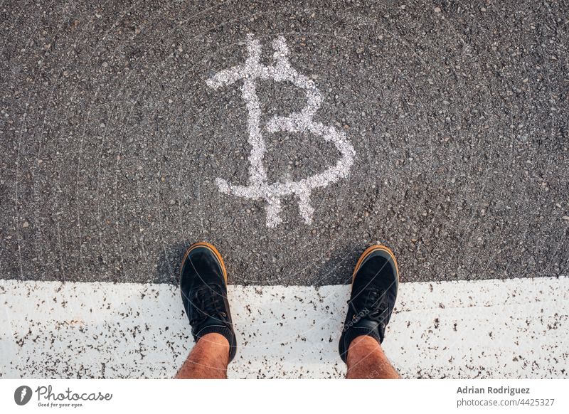 A person stands in front of the Bitcoin sign - crisis, finance, money Unrecognizable bit coin Sign Crisis Loose change Cryptocurrency Money Financial Industry