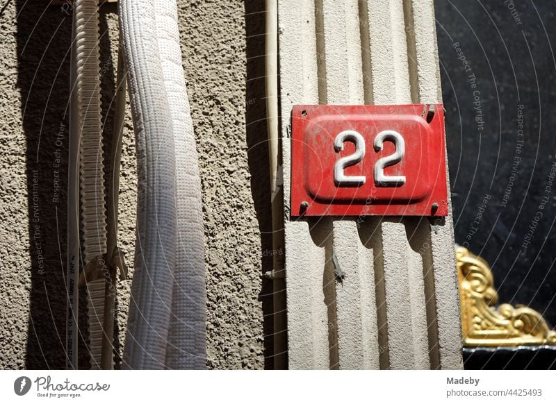 House number 22 as a tin sign in white on red at an old house in sunshine in Taksim in Istanbul at the Bosporus in Turkey twenty-two Red White Tin