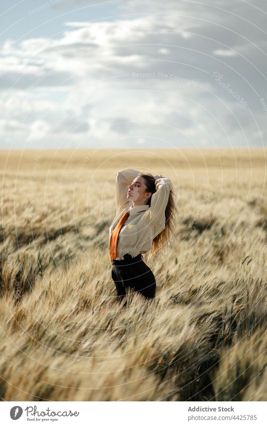 Stylish model in wheat field under cloudy sky mindfulness style nature spike eyes closed woman countryside tie dreamy concentrate atmosphere air shiny vegetate