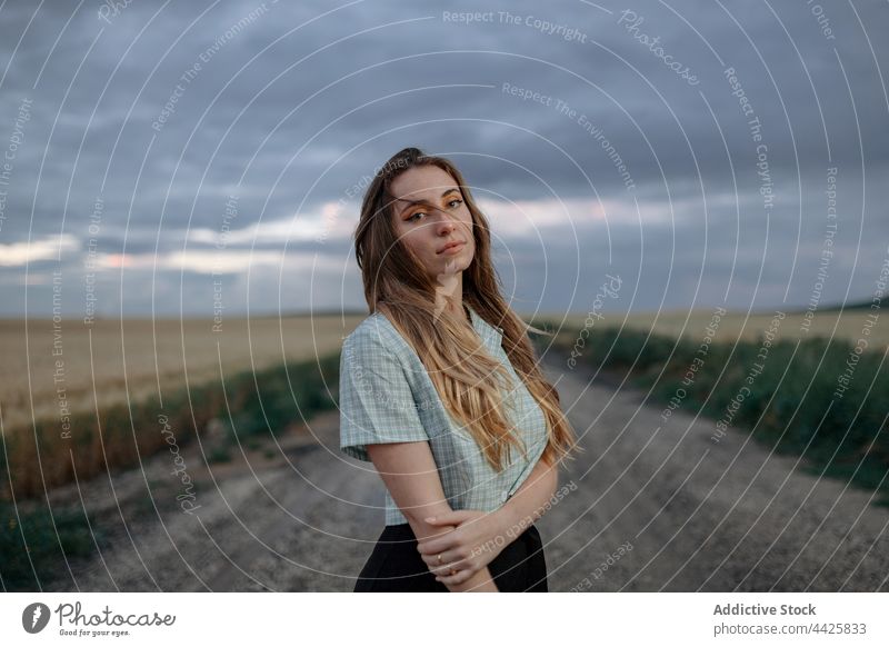 Stylish model in field under cloudy sky mindfulness style nature woman countryside dreamy concentrate atmosphere meadow vegetate grow reflective cereal