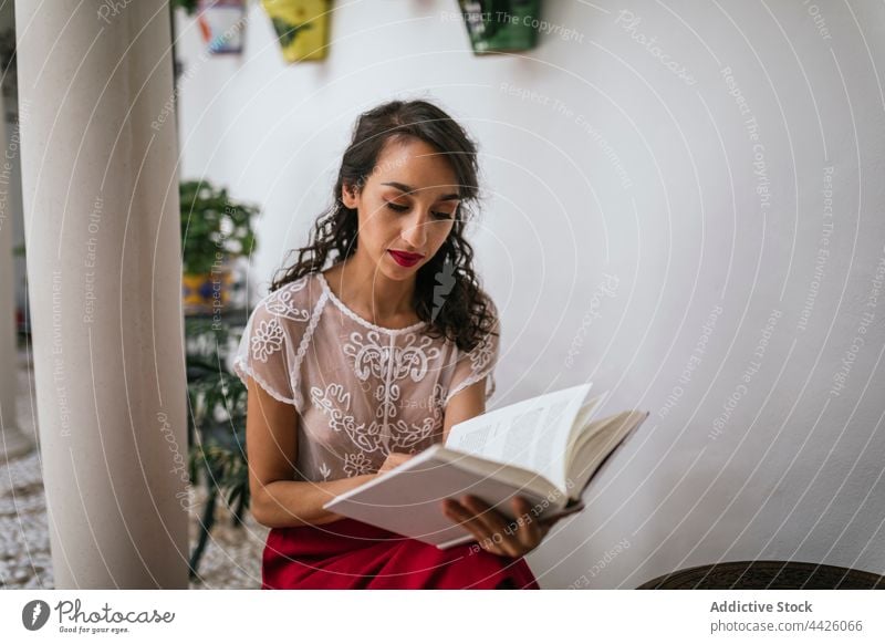Ethnic woman reading book in patio story style content novel interesting chill female ethnic fiction bookworm focus knowledge textbook weekend wisdom pastime