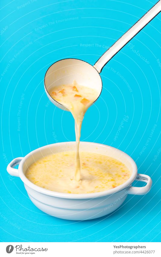 Greek soup in a white enamel bowl. Pouring soup from the ladle avgolemono background blue chicken chicken soup close-up color creamy cuisine cut out delicious