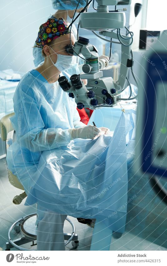 Ophthalmologist looking through microscope during eye operation in clinic ophthalmologist look through ocular attentive instrument patient woman hospital