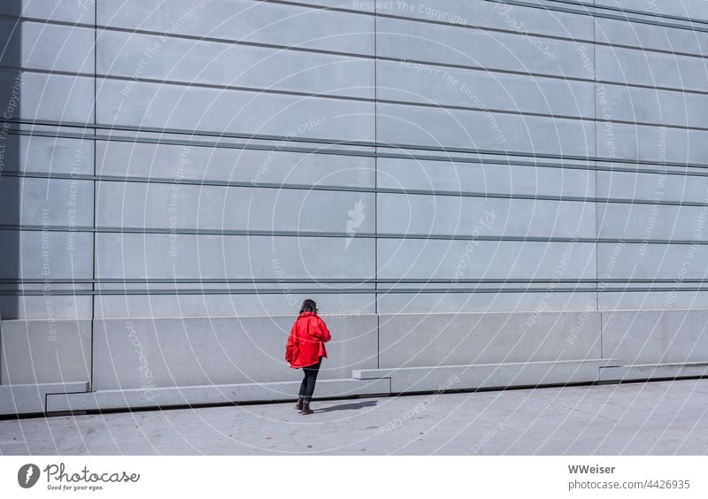 The young woman's red jacket glows against the structured façade of the modern museum Facade Architecture urban Modern Wall (building) lines Geometry Woman