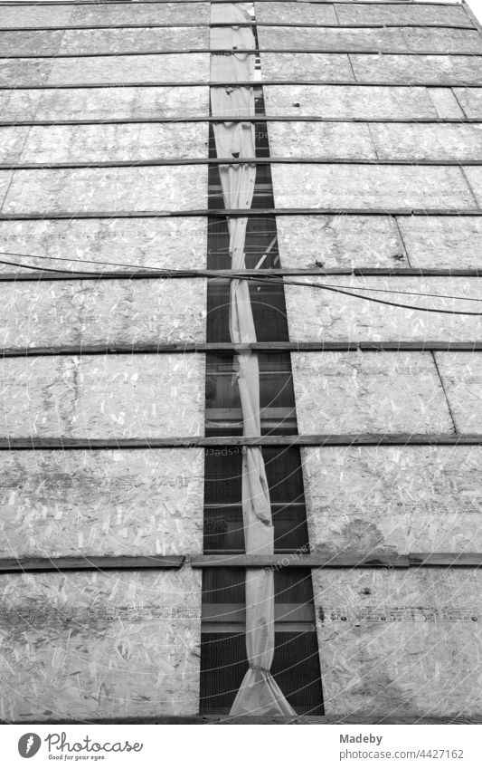 Facade cladding made of chipboard and old power cables in front of the facade of an old building in the Galata quarter in the Beyoğlu district of Istanbul on the Bosporus in Turkey, photographed in classic black and white