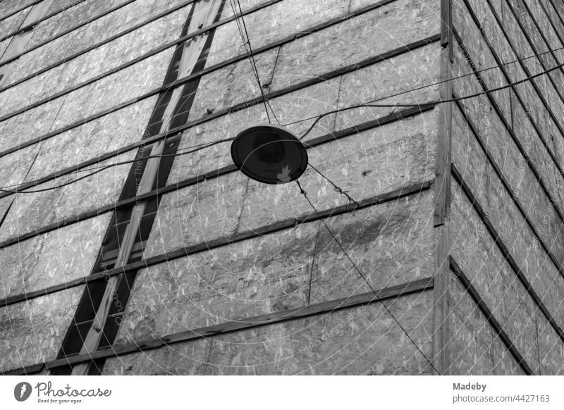 Street lighting on old power cables in front of a façade cladding with chipboard in the Galata quarter in the Beyoğlu district of Istanbul on the Bosphorus in Turkey, photographed in neo-realist black and white