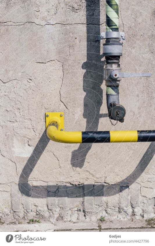 Pipe of a pumping station and safety bar in yellow black on a concrete wall. Conduit Pumping station Deserted Exterior shot Wall (building) Colour photo