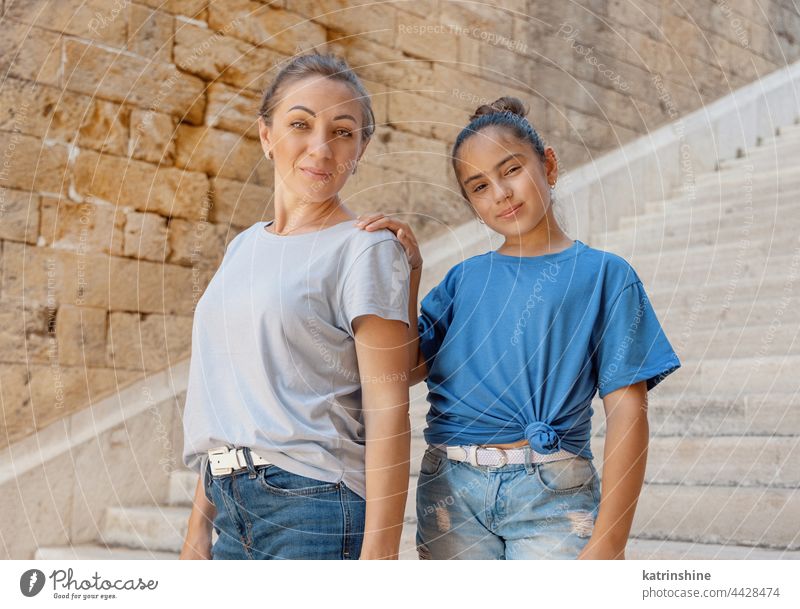 Mother and daughter standing on stone stairs outside Child kid girl mockup outdoor middle-aged woman schooler wearing t-shirts Stone embrace mom motherhood Blue