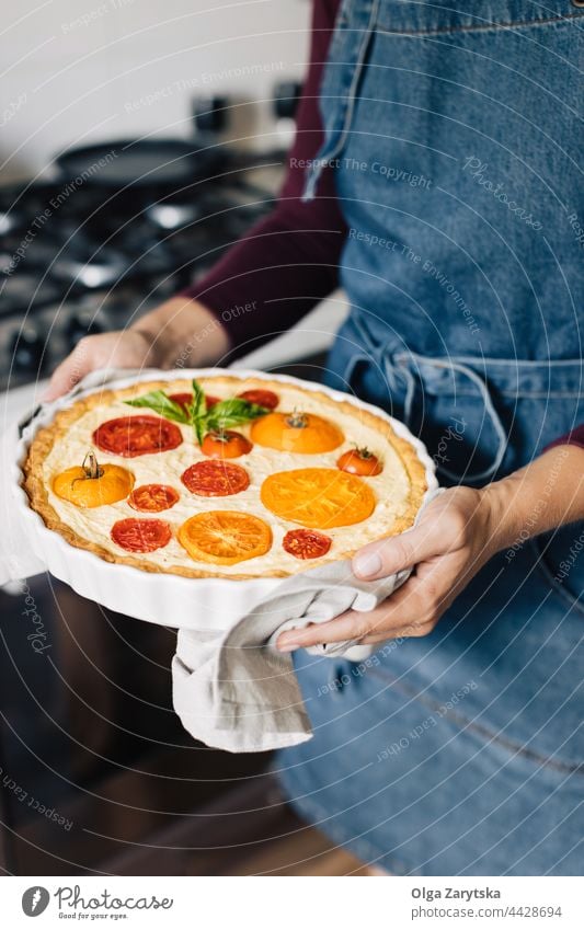 Female hands holding cheese and tomato quiche. tart red yellow ceramic dish pot seasonal basil baked circle food napkin