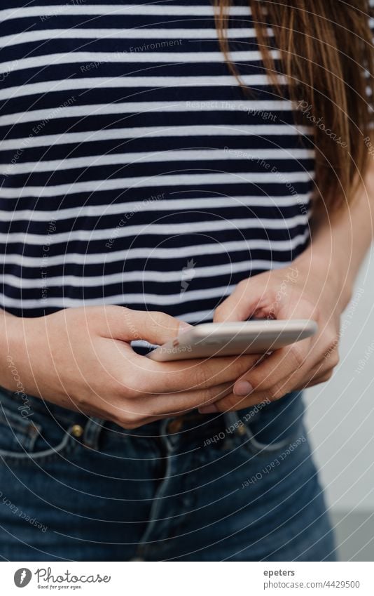 Young woman holding smartphone, only hands are shown Easygoing garments gen z Participation Jeans Striped T-shirt technology Technology Unrecognizable using