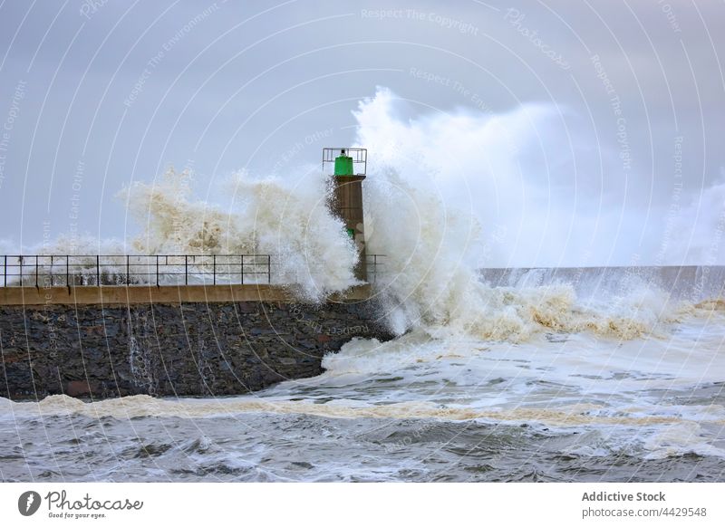 Powerful stormy sea and lighthouse wave power beacon tower ocean energy foam crash splash coast spain asturias viavelez port water seascape shore breakwater