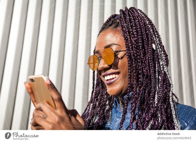 Black woman with braids using smartphone afro style cheerful urban trendy gadget african american black ethnic female mobile young hipster browsing millennial