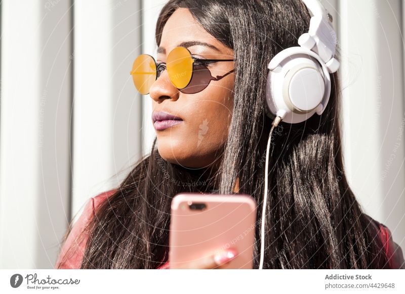 Stylish black woman with smartphone listening to music headphones style urban trendy gadget fashion female african american ethnic young mobile sunglasses
