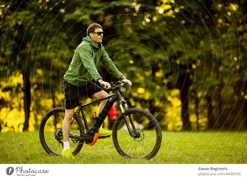 Young man riding ebike in the park active battery bicycle biker biking black cyclist e-bike eco ecologic ecology electric electro energy engine equipment