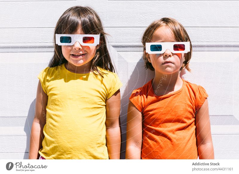 Happy trendy kids in 3D glasses standing on wall three dimensional entertain 3d fun happy smile eyewear showtime joy child children casual girls watch movie