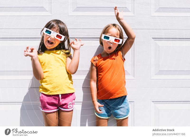 Happy trendy kids in 3D glasses standing on wall three dimensional entertain 3d fun happy smile eyewear showtime joy child children casual girls watch movie