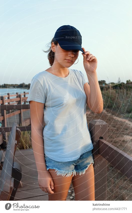 Teen girl in dark blue baseball cap and t-shirt outdoor teenager adolescent Caucasian mockup sea visor wearing t-shirts teen girl sidewalk bridge childhood