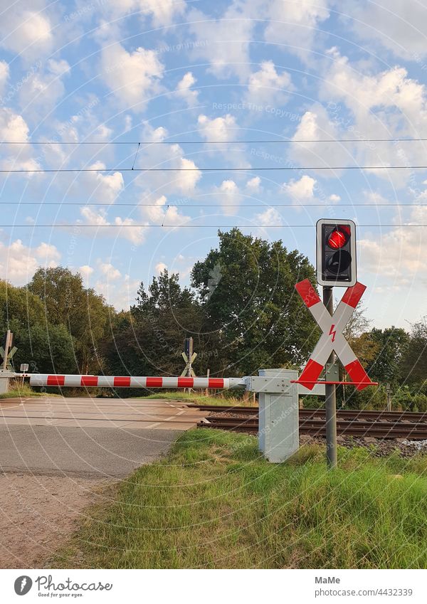 Level crossing with closed half-barriers on an agricultural road Railroad crossing Closed St. Andrew's cross with lightning electrical catenary power box